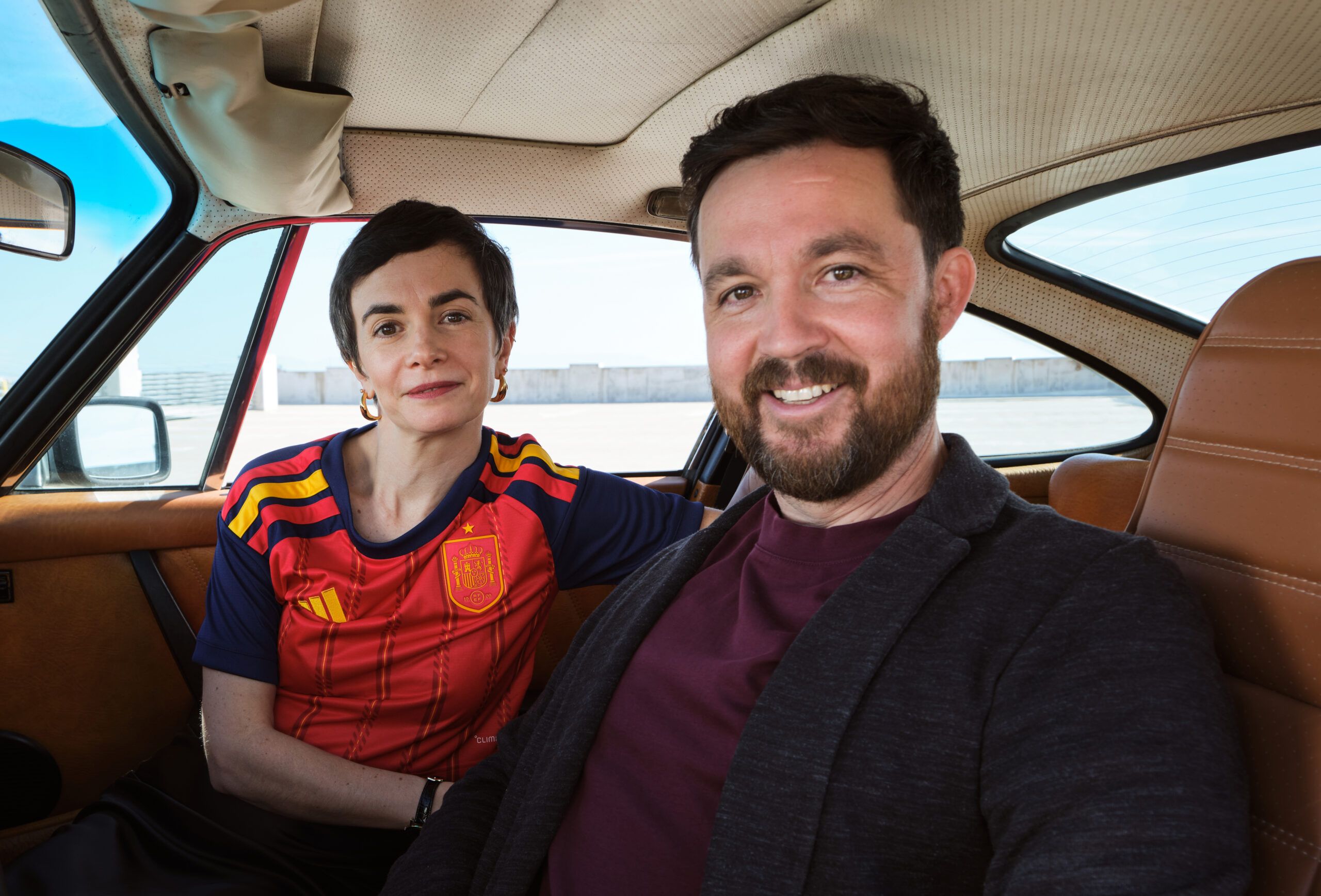 A portrait of JD Jurentkuff and Agathe Guerrier sitting in the front seats of a vintage Porsche 911.