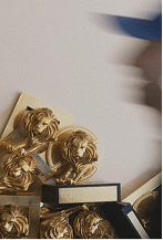 A stack of Cannes Lions trophies with a blurred profile of someone walking past