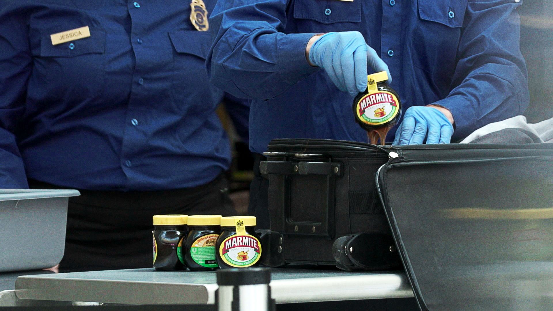 A photo of airport security officers taking jars of marmite out of a suitcase